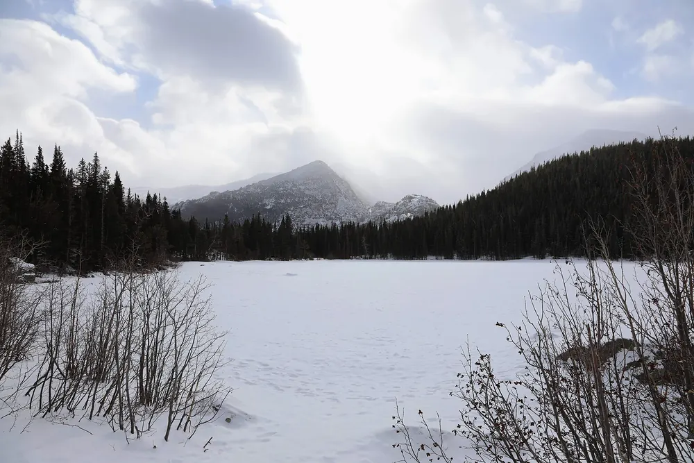 Bear Lake in January beneath snow-covered forest in Rocky Mountain National Park